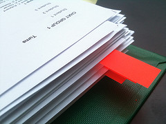 A stack of papers, a few sheets marked with red tabs.
