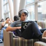 Student in the library using a laptop wearing headphones