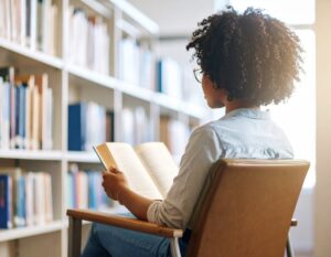 black student reading in library sitting in a chair